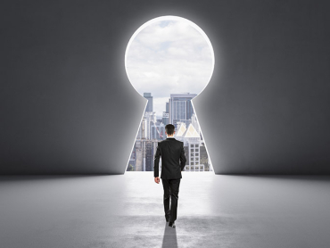 Back view of businessman walking in concrete interior with abstract keyhole window with city view. Key to success and career growth concept. Mock up place